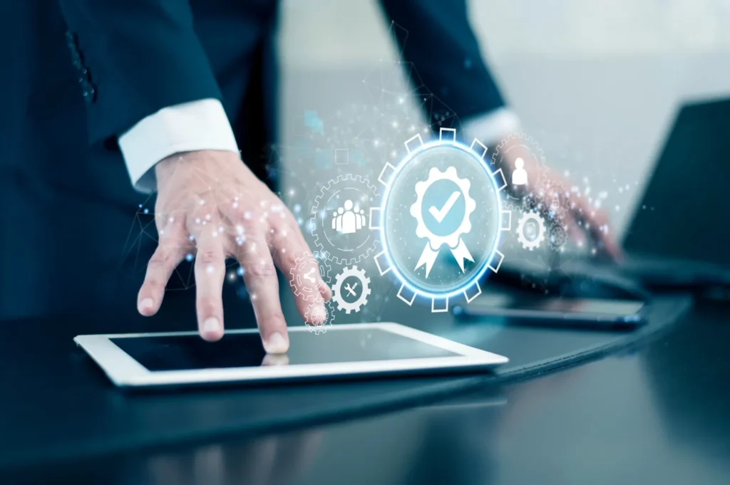 Main d’un professionnel utilisant une tablette avec une icône de certification numérique, symbolisant l’audit Qualiopi de surveillance 2025.